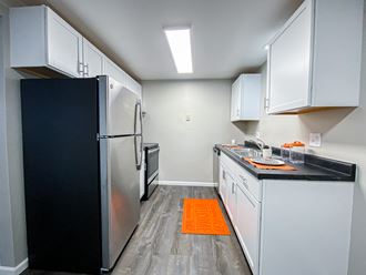 a kitchen with white cabinets and stainless steel appliances and a black refrigerator