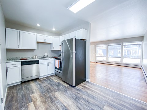 A kitchen with a black refrigerator and wooden floors.