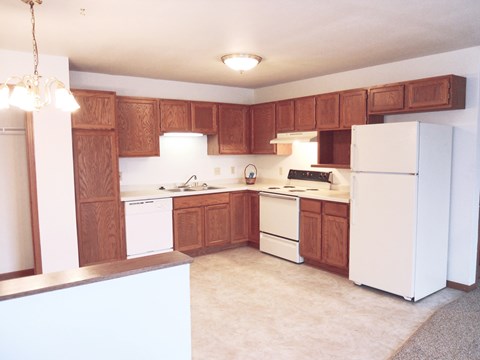 A kitchen with white appliances and wooden cabinets.