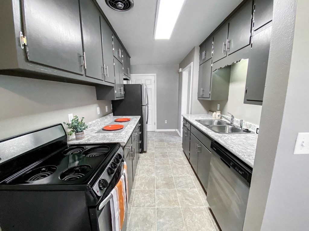 an empty kitchen with black appliances and stainless steel cabinets