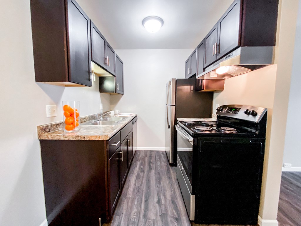 a kitchen with black appliances and dark cabinets and a stove and refrigerator