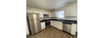an empty kitchen with stainless steel appliances and white cabinets