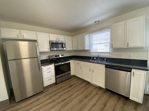 an empty kitchen with stainless steel appliances and white cabinets