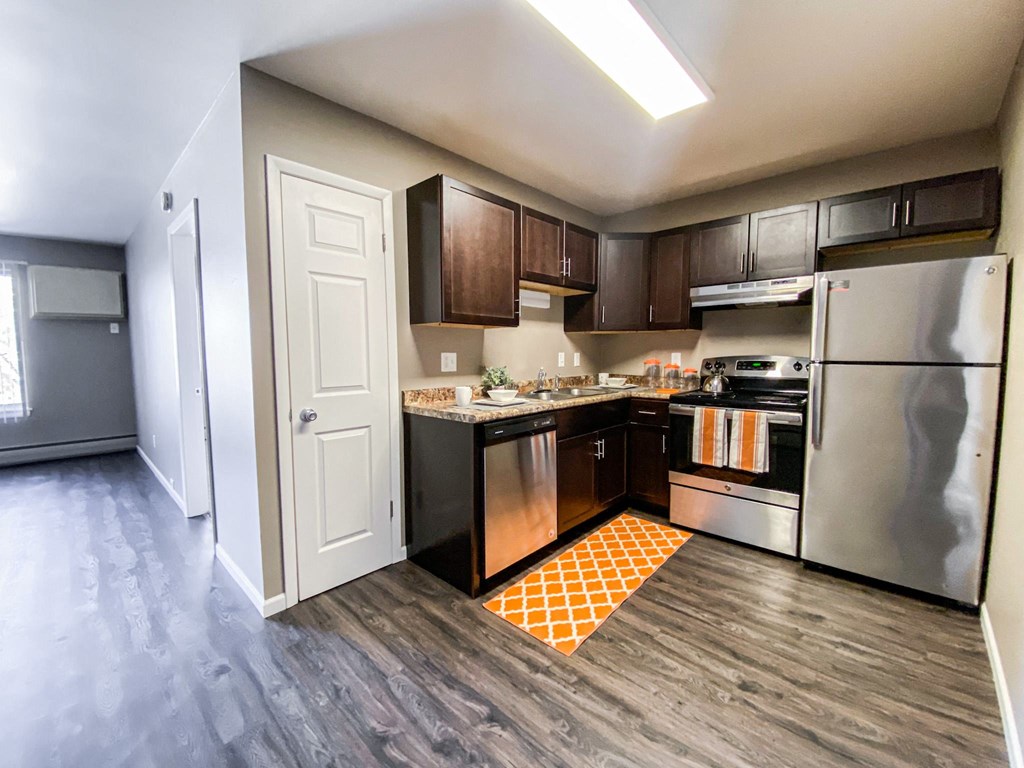 an empty kitchen with stainless steel appliances and wooden cabinets