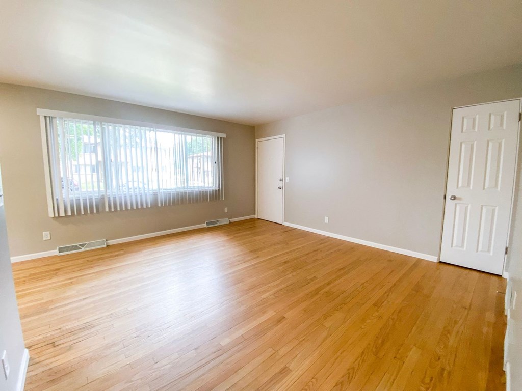 an empty living room with wood floors and a window