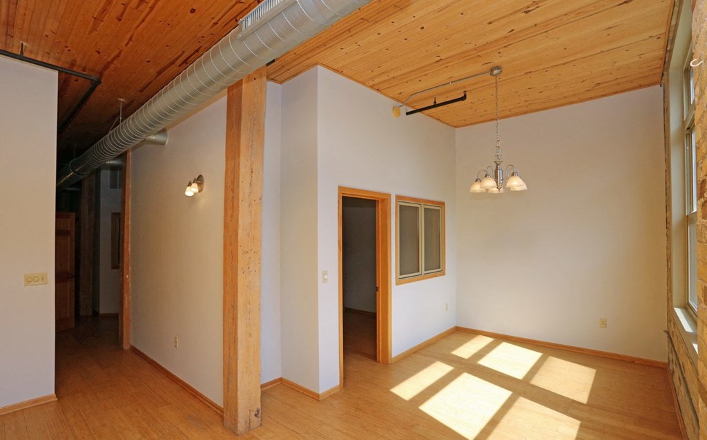 a living room with white walls and wooden floors and a door