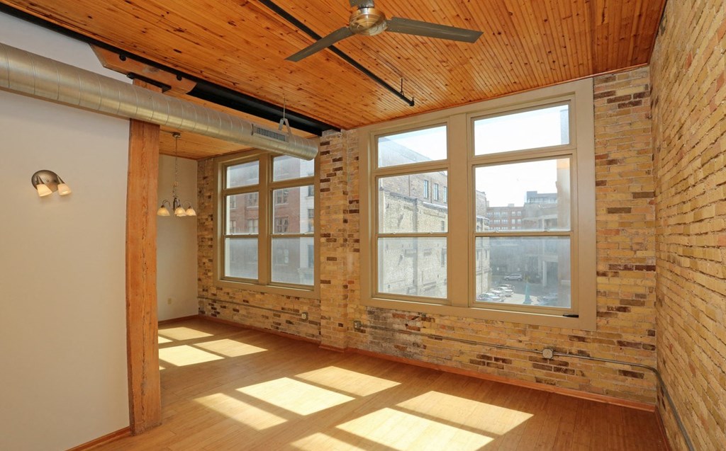 an empty room with a brick wall and large windows