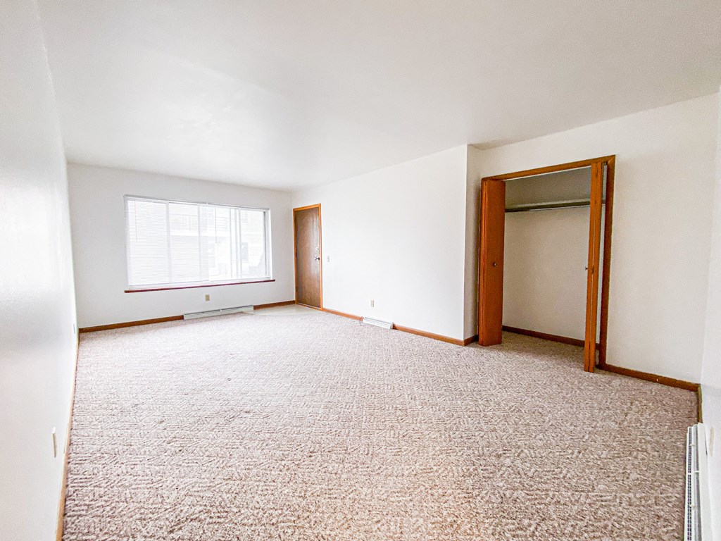 an empty living room with a door to a closet