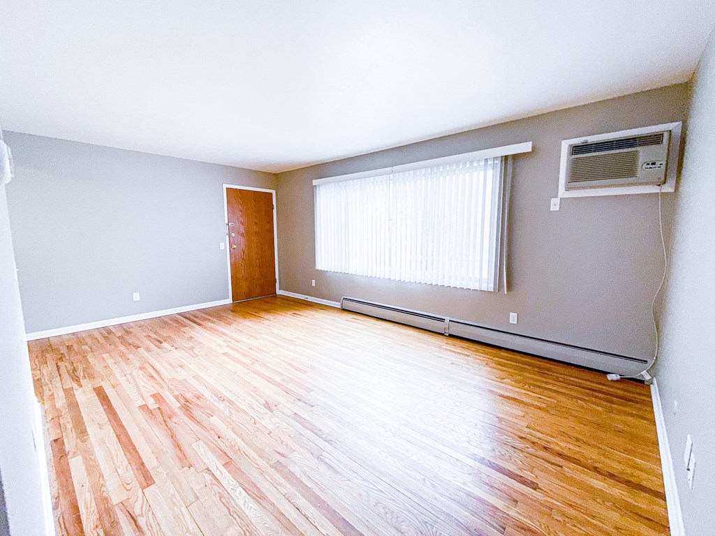 an empty living room with wood floors and a window