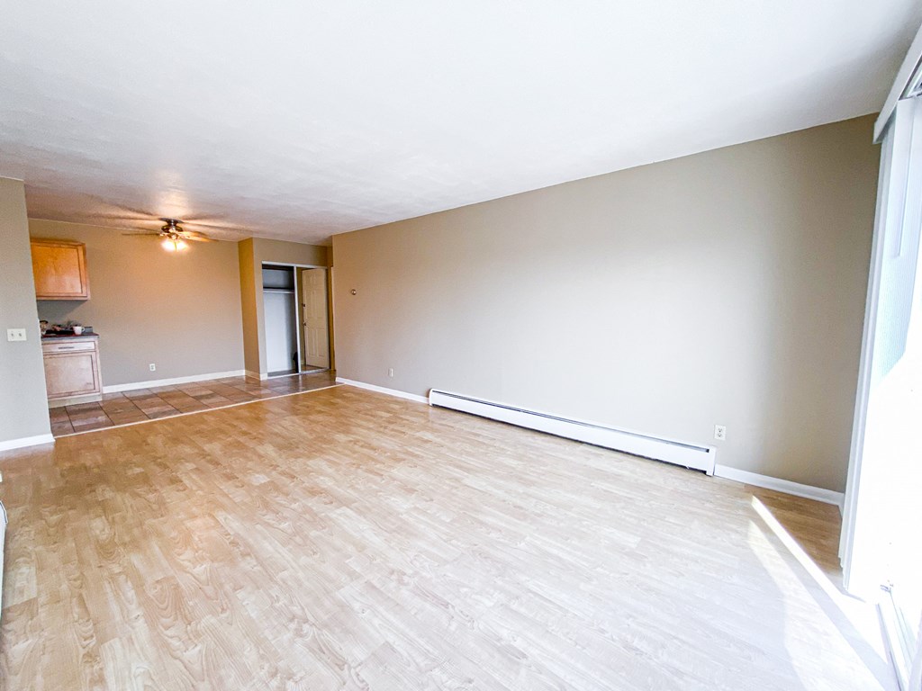 an empty living room with wood flooring and a ceiling fan