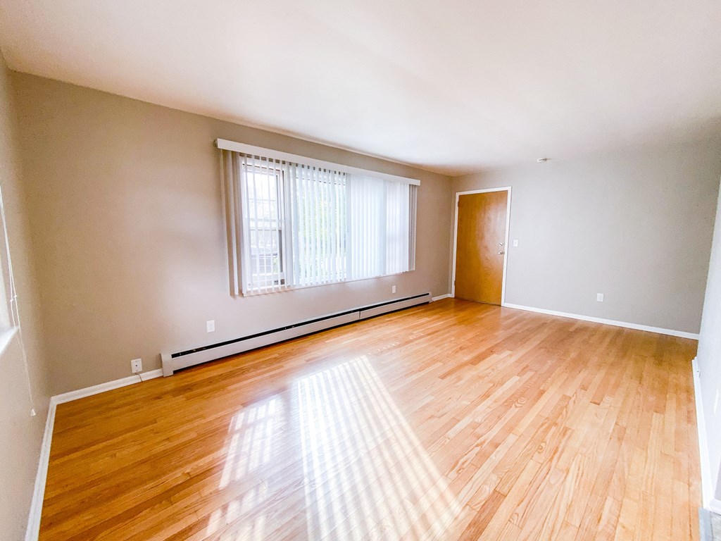 an empty living room with wood floors and a window