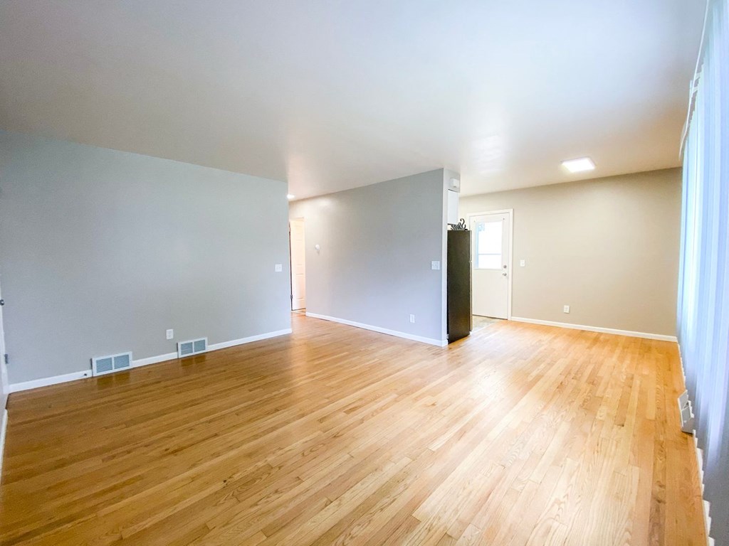 the living room and dining room of an empty house with wood floors