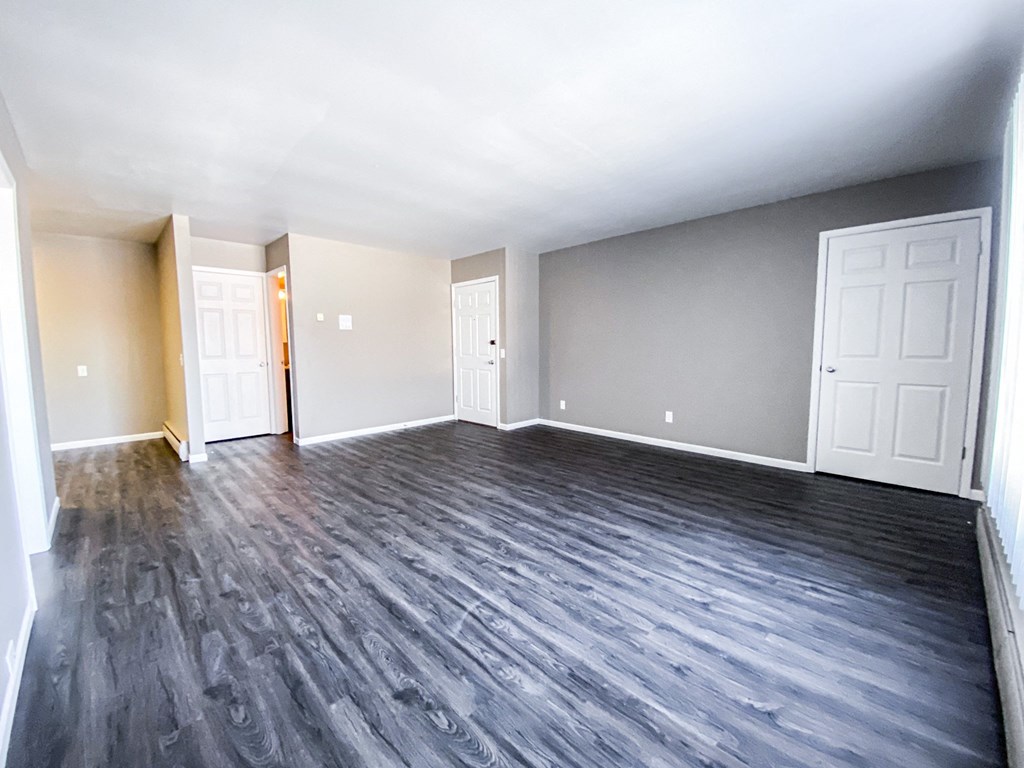 an empty living room with wood floors and white doors