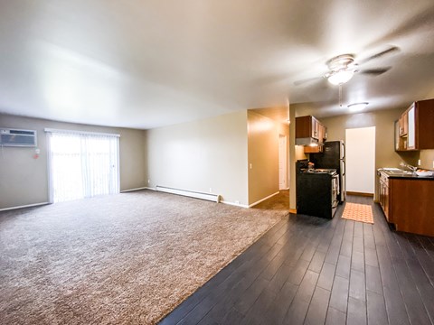 an empty living room with a rug and a kitchen