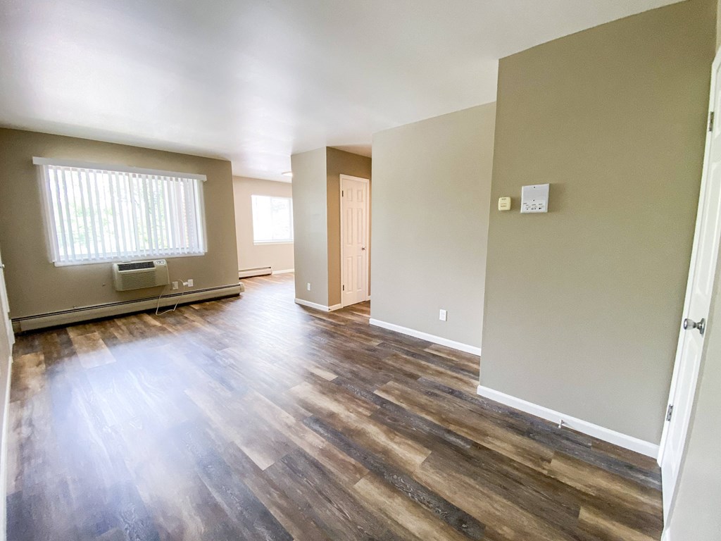 an empty living room with hard wood floors and a window