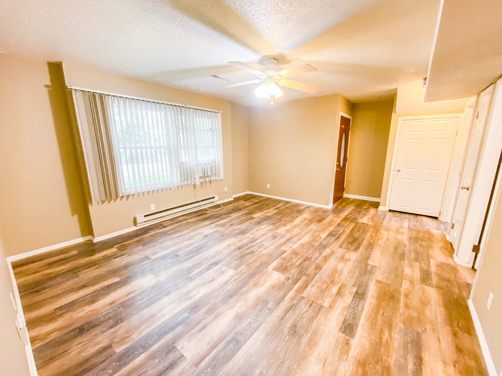 an empty living room with wood floors and a ceiling fan