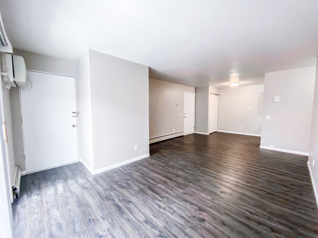 an empty living room with white walls and wood flooring