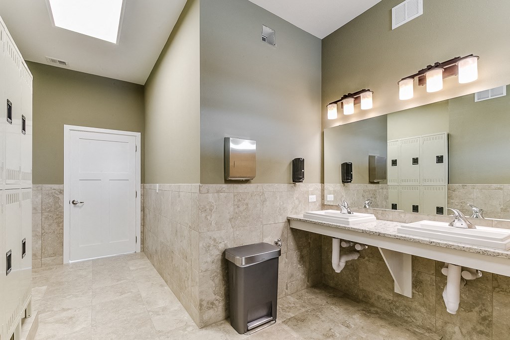 a bathroom with two sinks and a trash can
