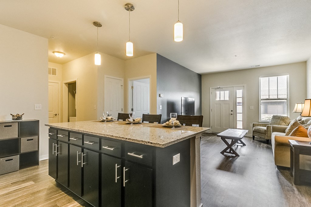 a kitchen with an island and a living room in the background
