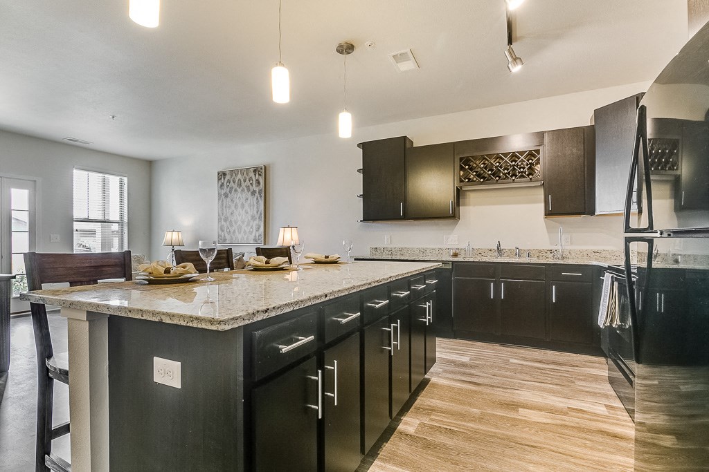 a kitchen with dark cabinets and a large island with granite countertops