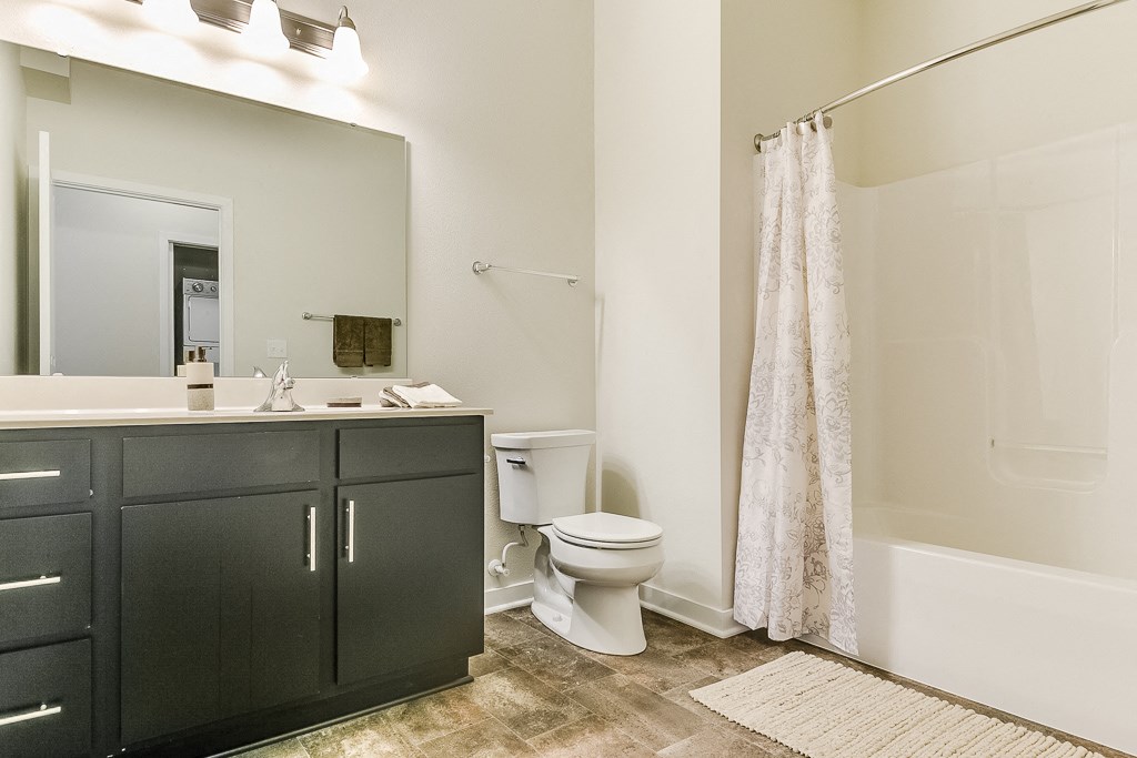 a bathroom with black cabinets and a white bathtub