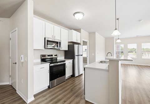 A modern kitchen with white cabinets and stainless steel appliances.