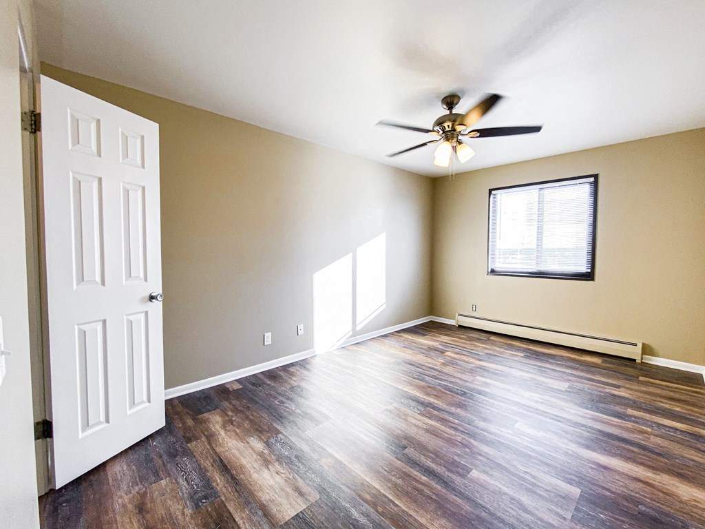 an empty living room with a ceiling fan and a window