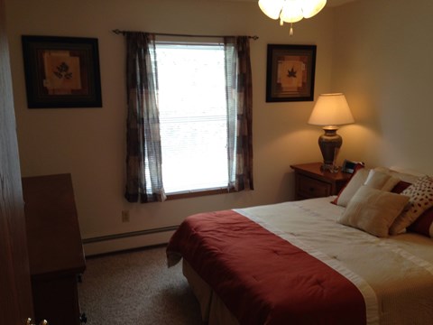 A bedroom with a bed, nightstand, and window.