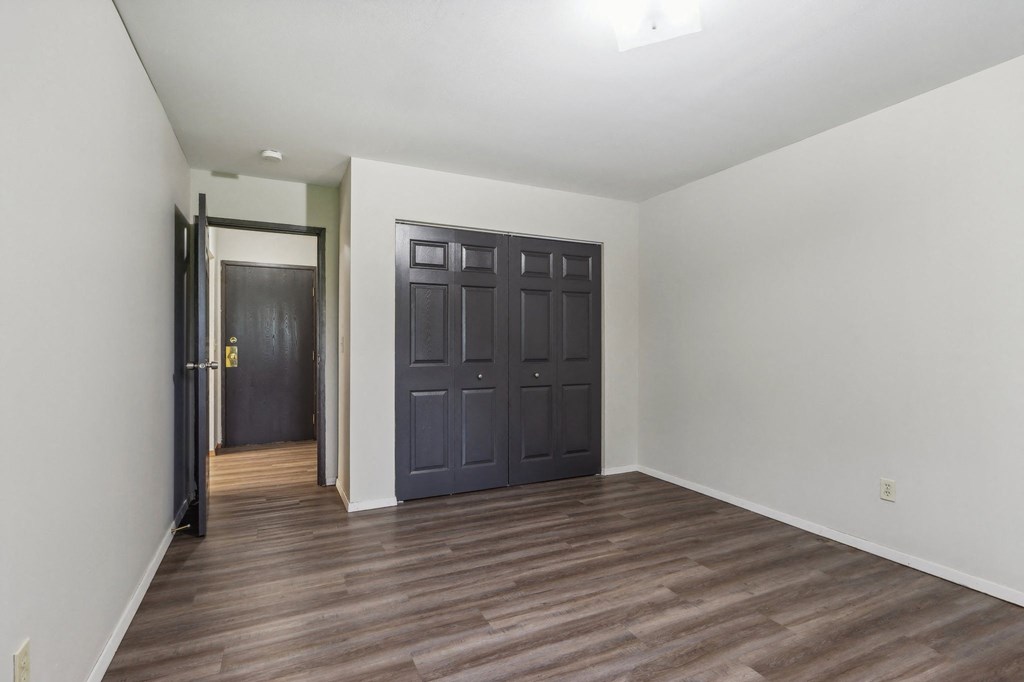 a empty room with a black door and wooden floors