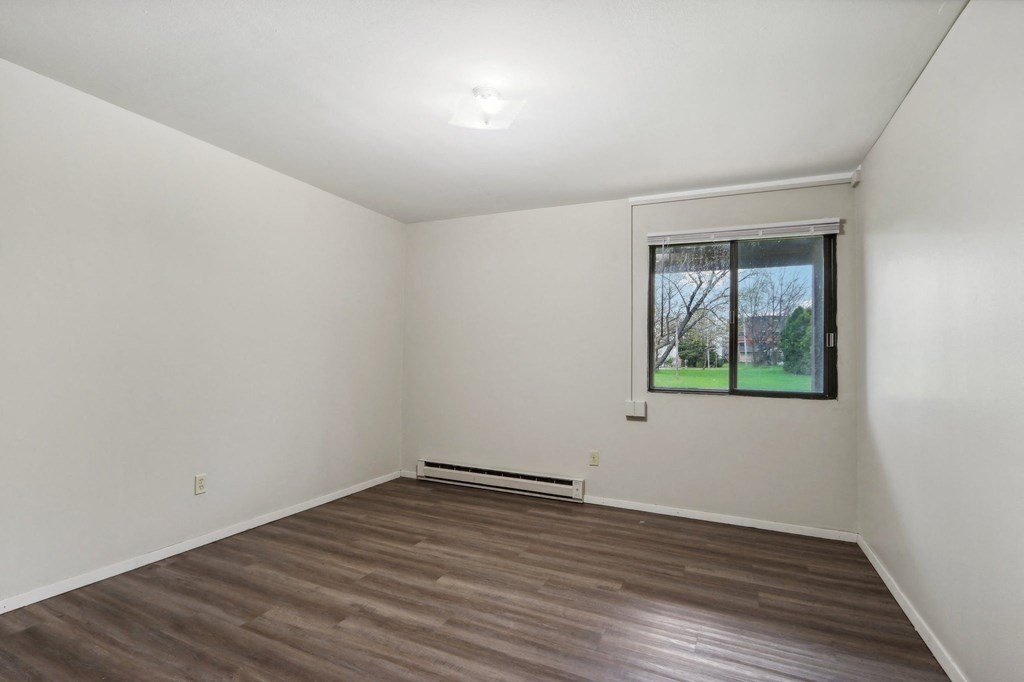an empty living room with wood floors and a window