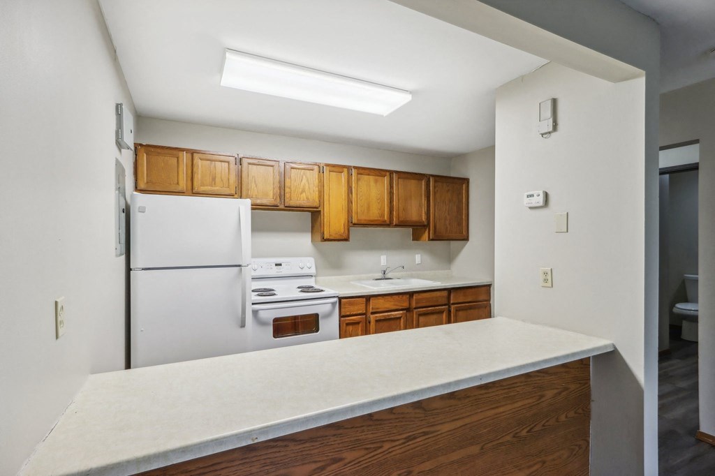 an empty kitchen with white appliances and wooden cabinets