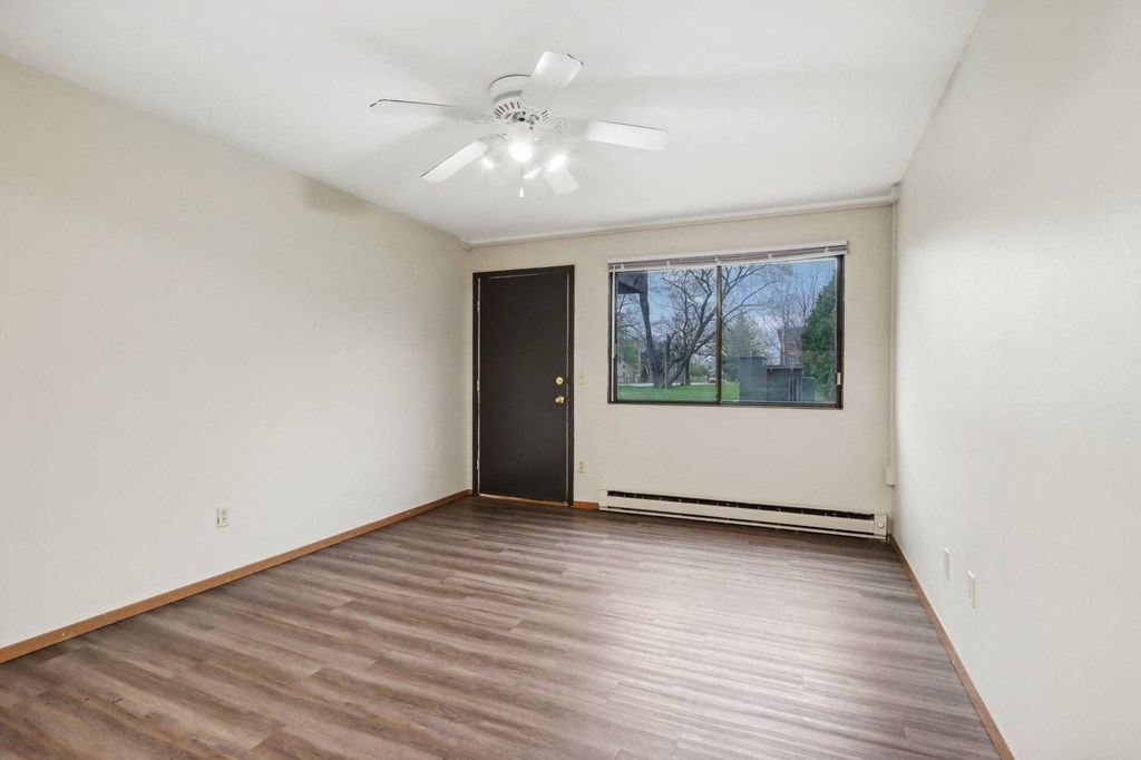an empty living room with wood flooring and a window