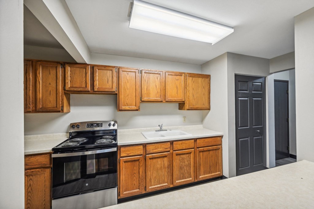 a kitchen with wooden cabinets and black appliances and a sink