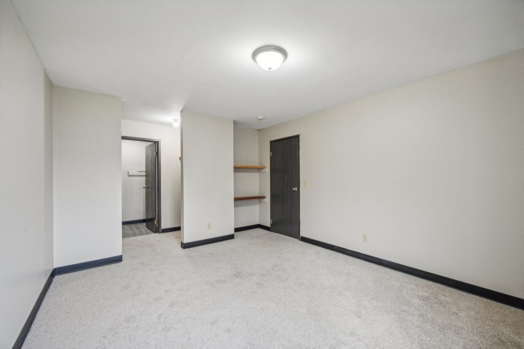 a empty room with white walls and a door to a closet