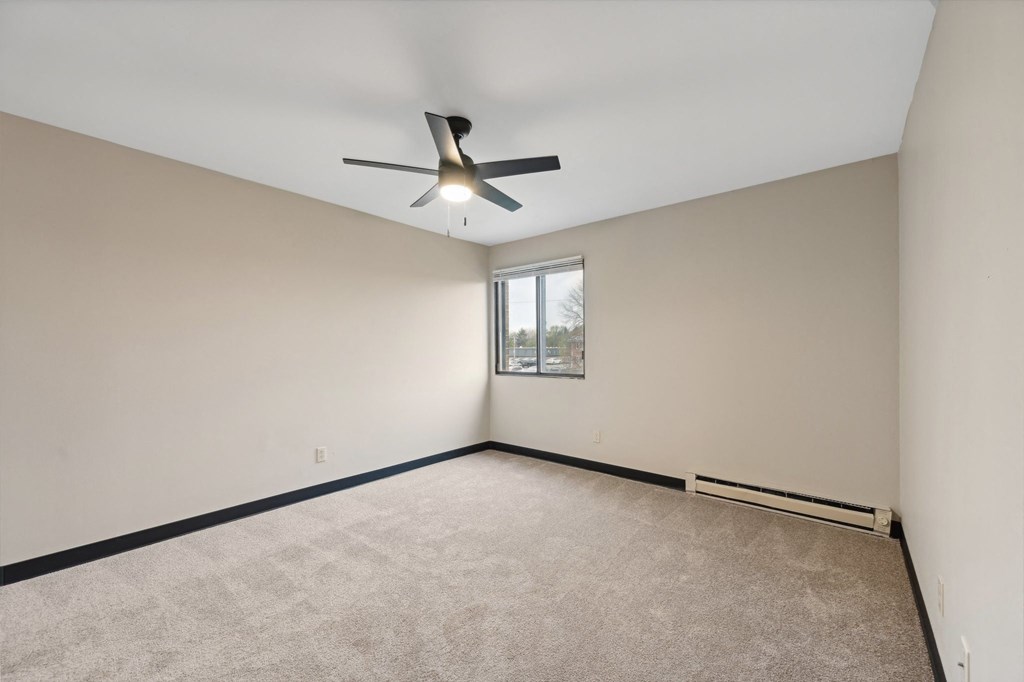 an empty living room with a ceiling fan and a window