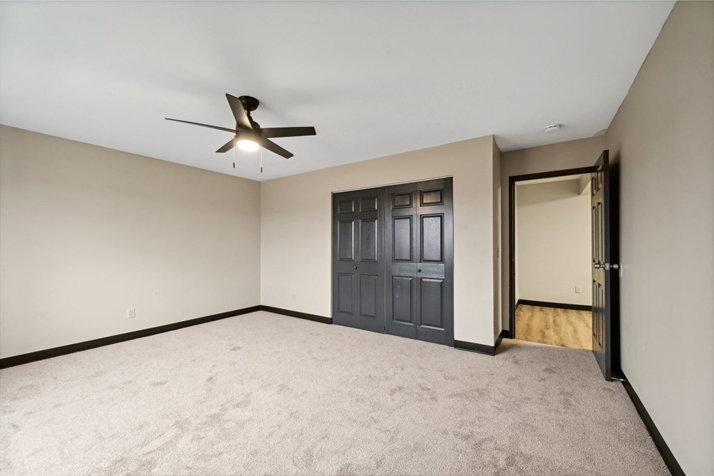 an empty living room with a ceiling fan and a door