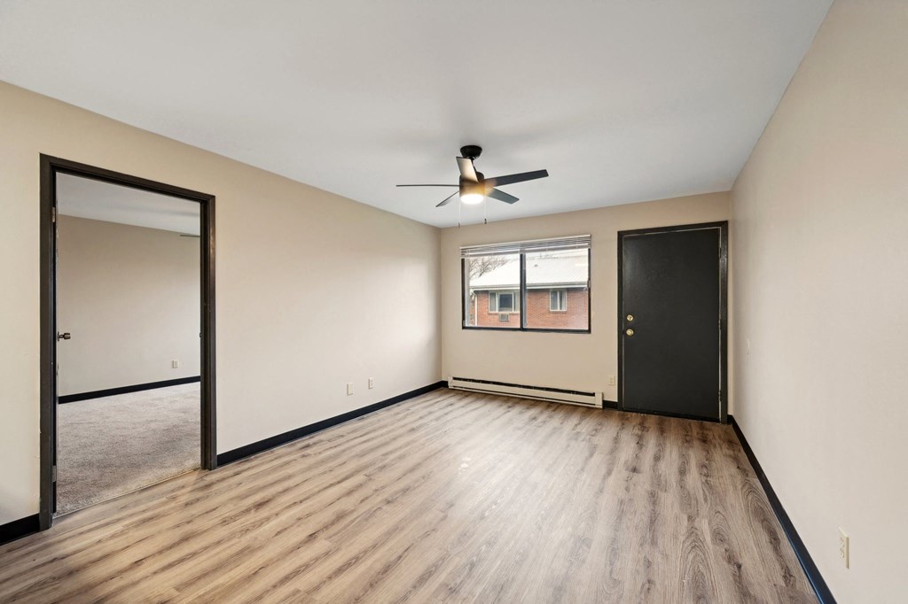 an empty living room with wood flooring and a ceiling fan