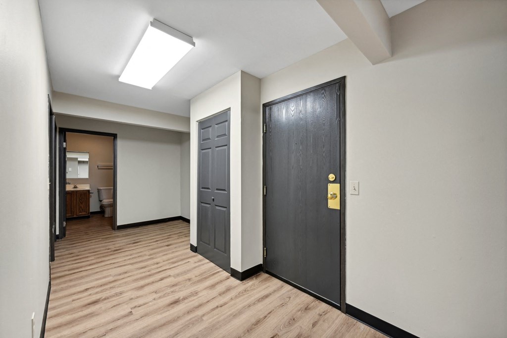 a room with two doors and a wooden floor and a door to a bathroom