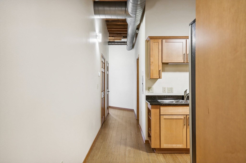 a long kitchen with wood floors and white walls and wooden cabinets