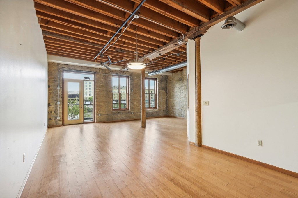 an empty living room with wood floors and exposed brick walls