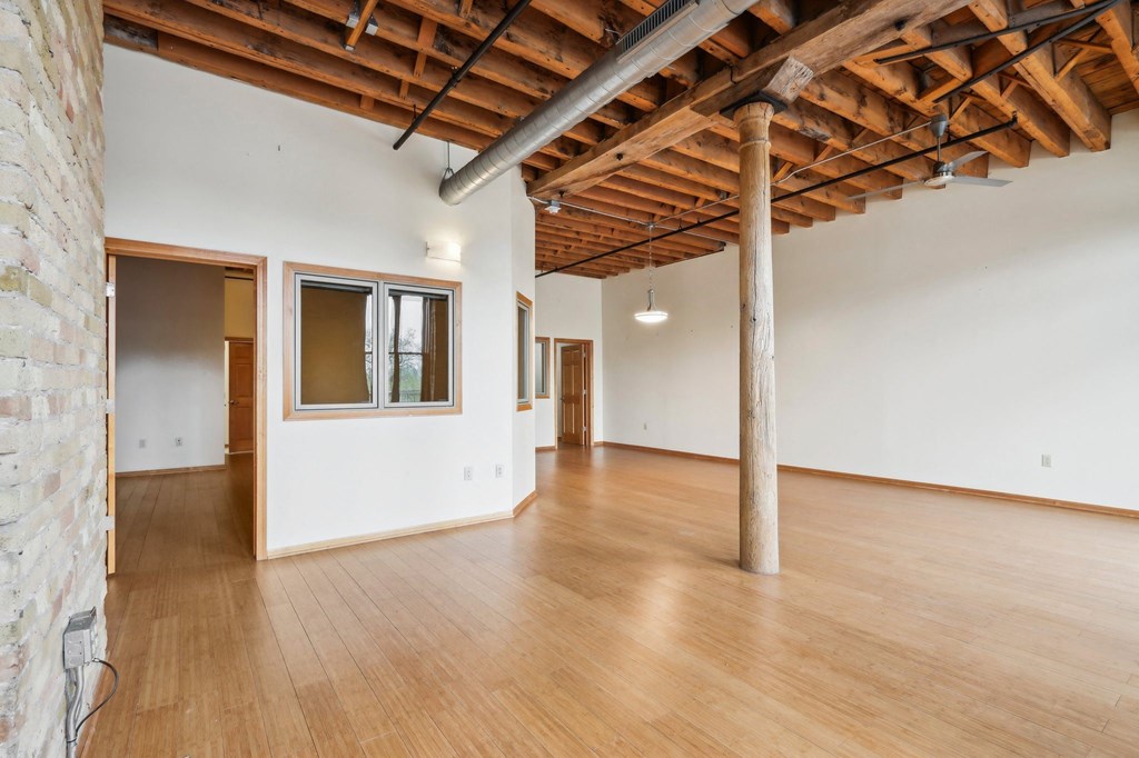 a large living room with wood floors and a exposed brick wall