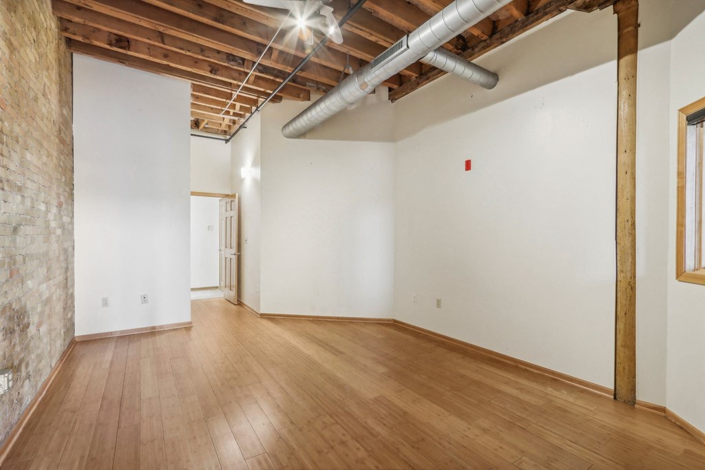 an empty living room with wood floors and white walls