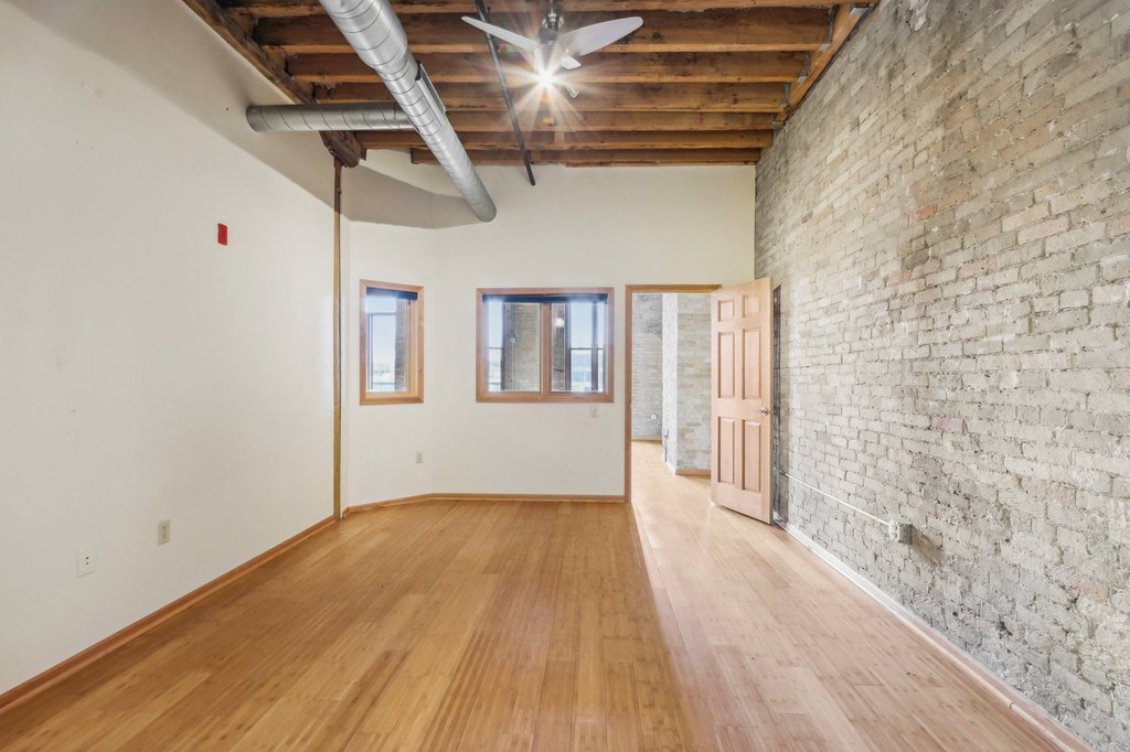 an empty living room with a brick wall and wood floors