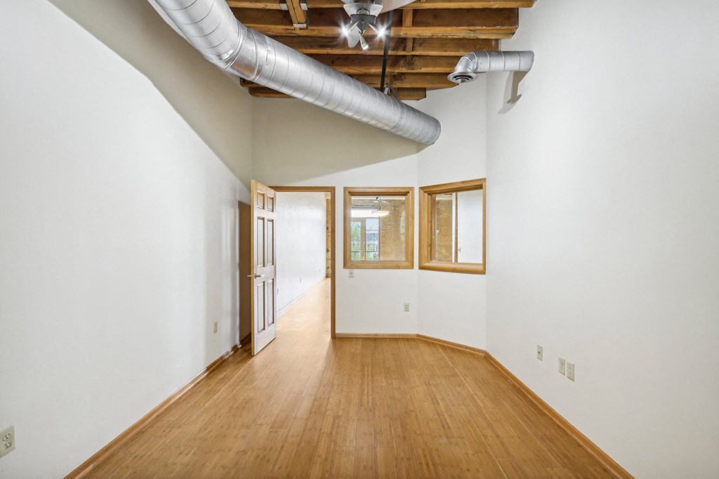 a living room with wood floors and white walls and a large window