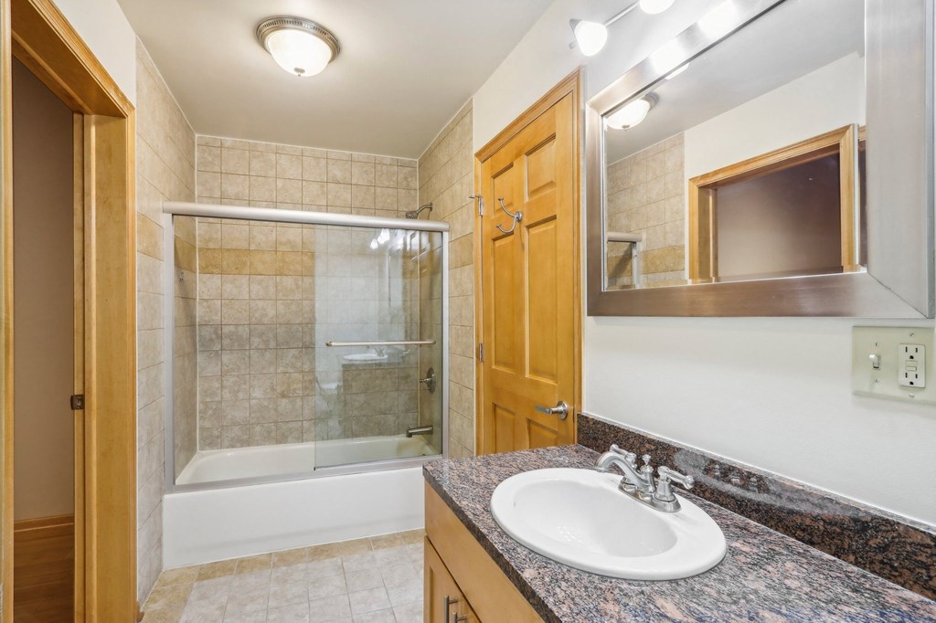 a bathroom with a sink and a shower and a mirror