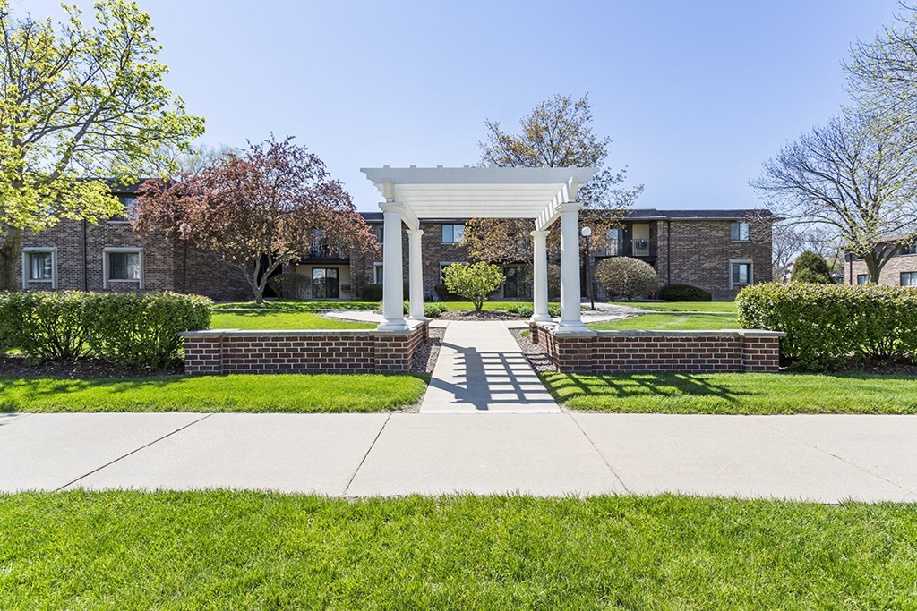 a white gazebo on a sidewalk in front of a brick building