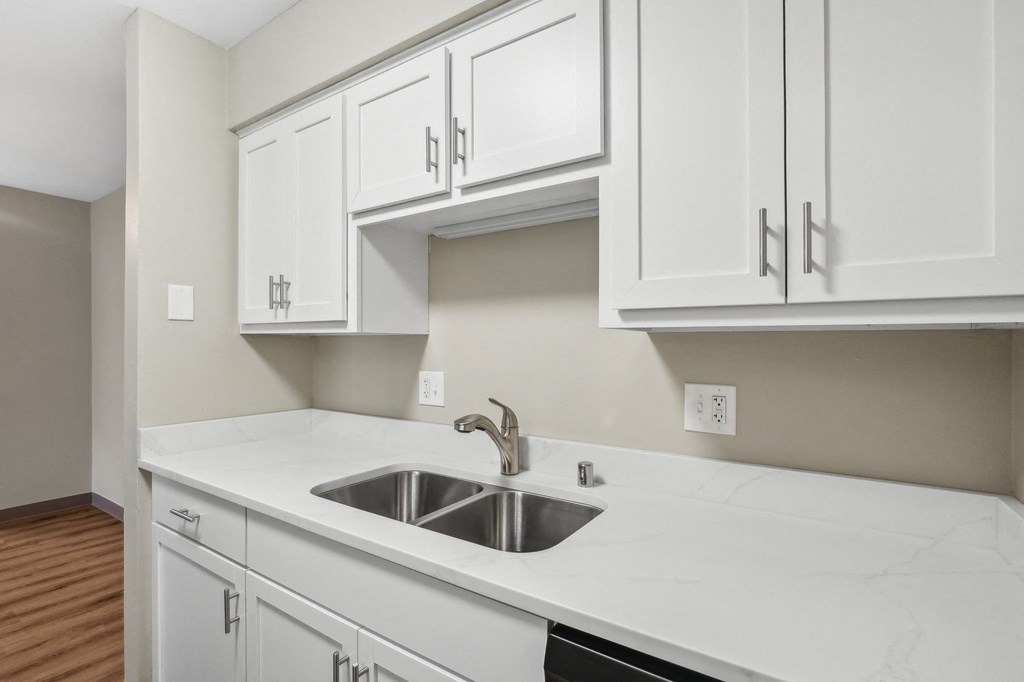 an empty kitchen with white cabinets and a sink