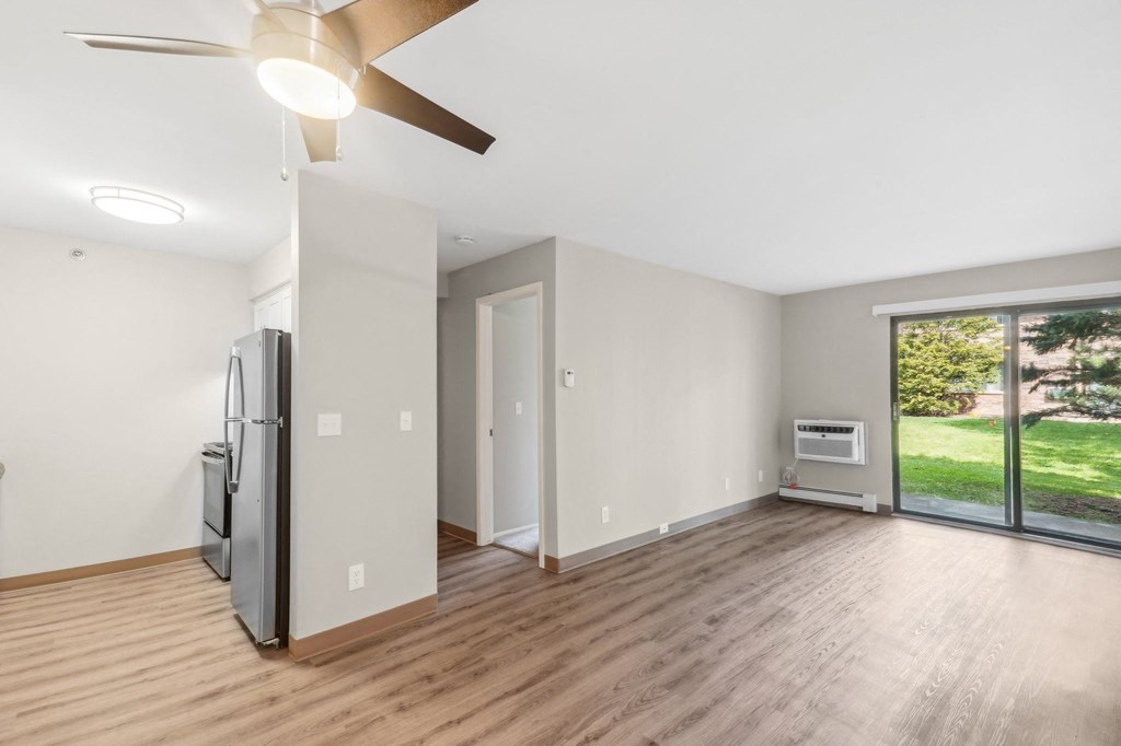 the living room of an empty house with a large window and a refrigerator