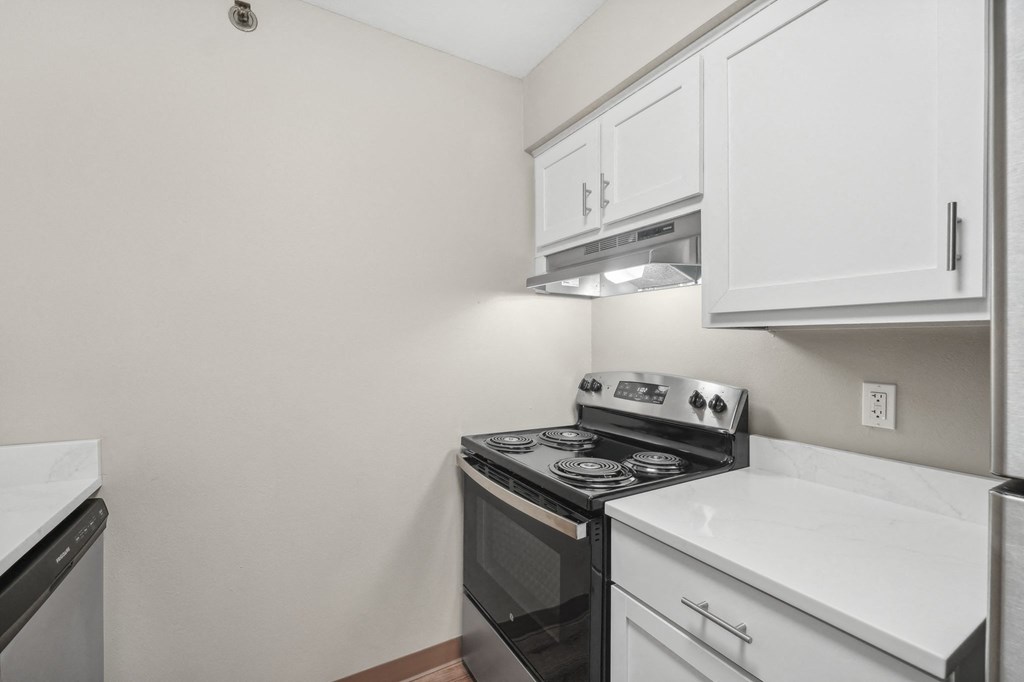 an empty kitchen with white cabinets and a black stove and oven