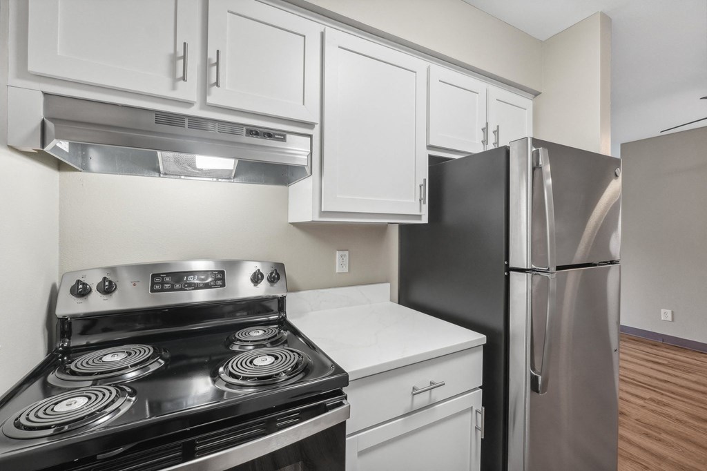 an empty kitchen with stainless steel appliances and white cabinets